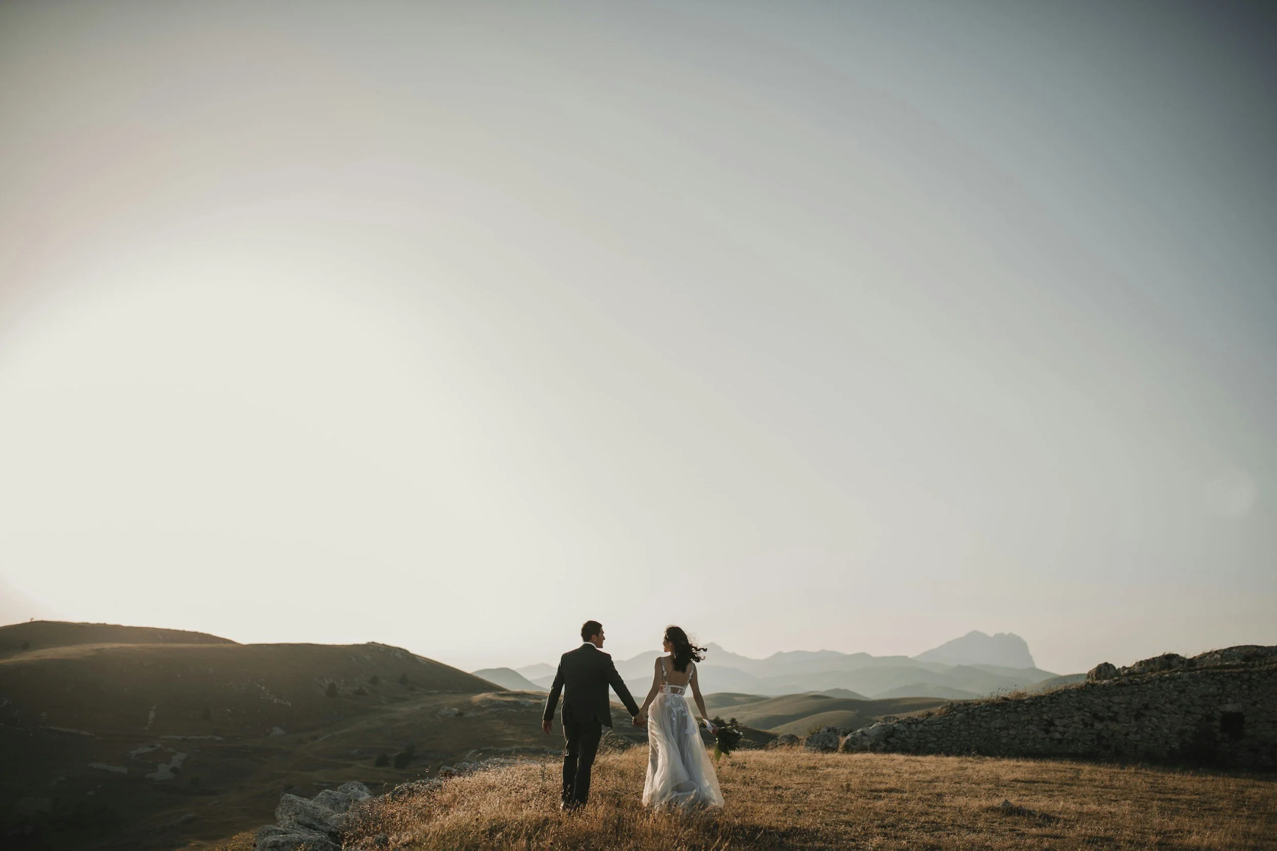 Couple walking hand in hand through golden hills